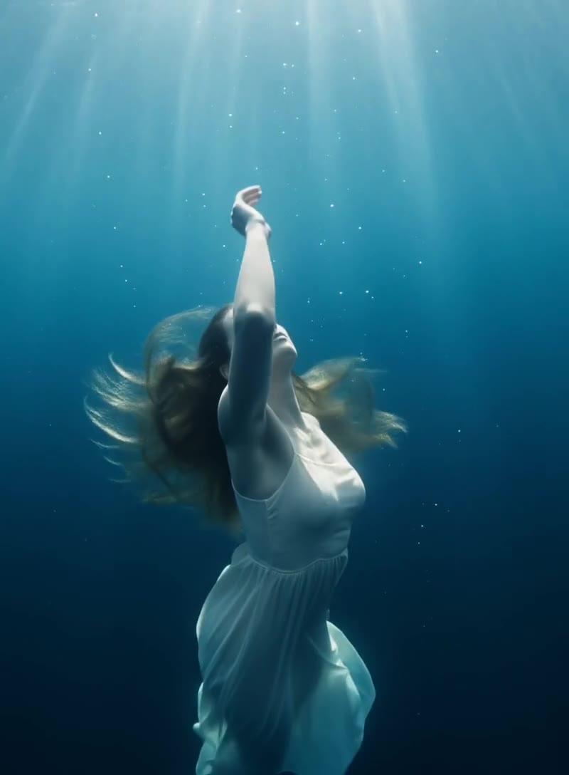 Woman in a flowing dress submerged underwater