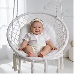 Cute baby sitting in a white hanging swing, smiling in a soft studio setting