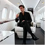 Stylish man sitting inside a luxury private jet holding a drink, representing premium lifestyle and elegance.