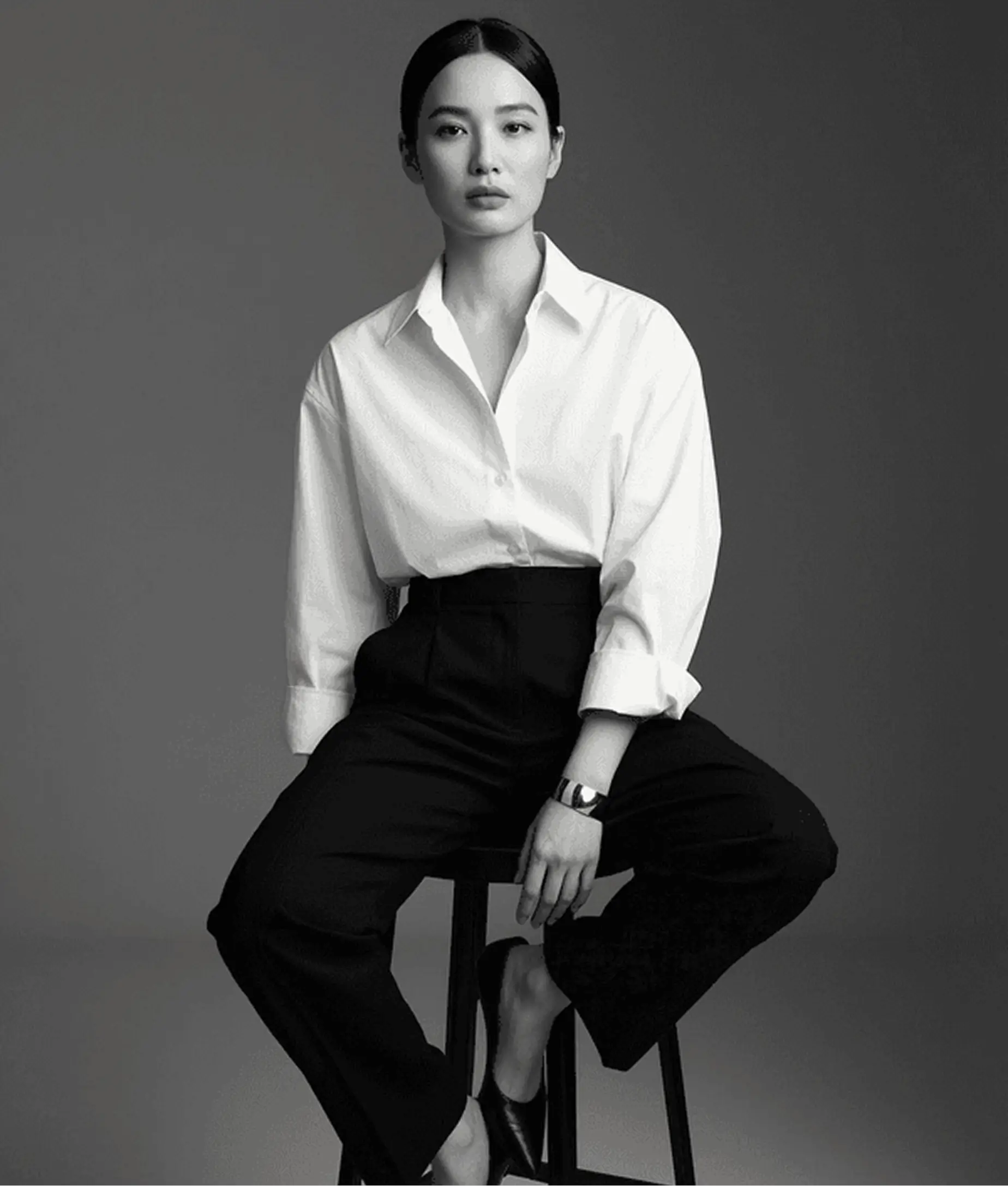 AI model photography example showing Asian woman in black and white editorial fashion shoot wearing white shirt and black skirt seated pose