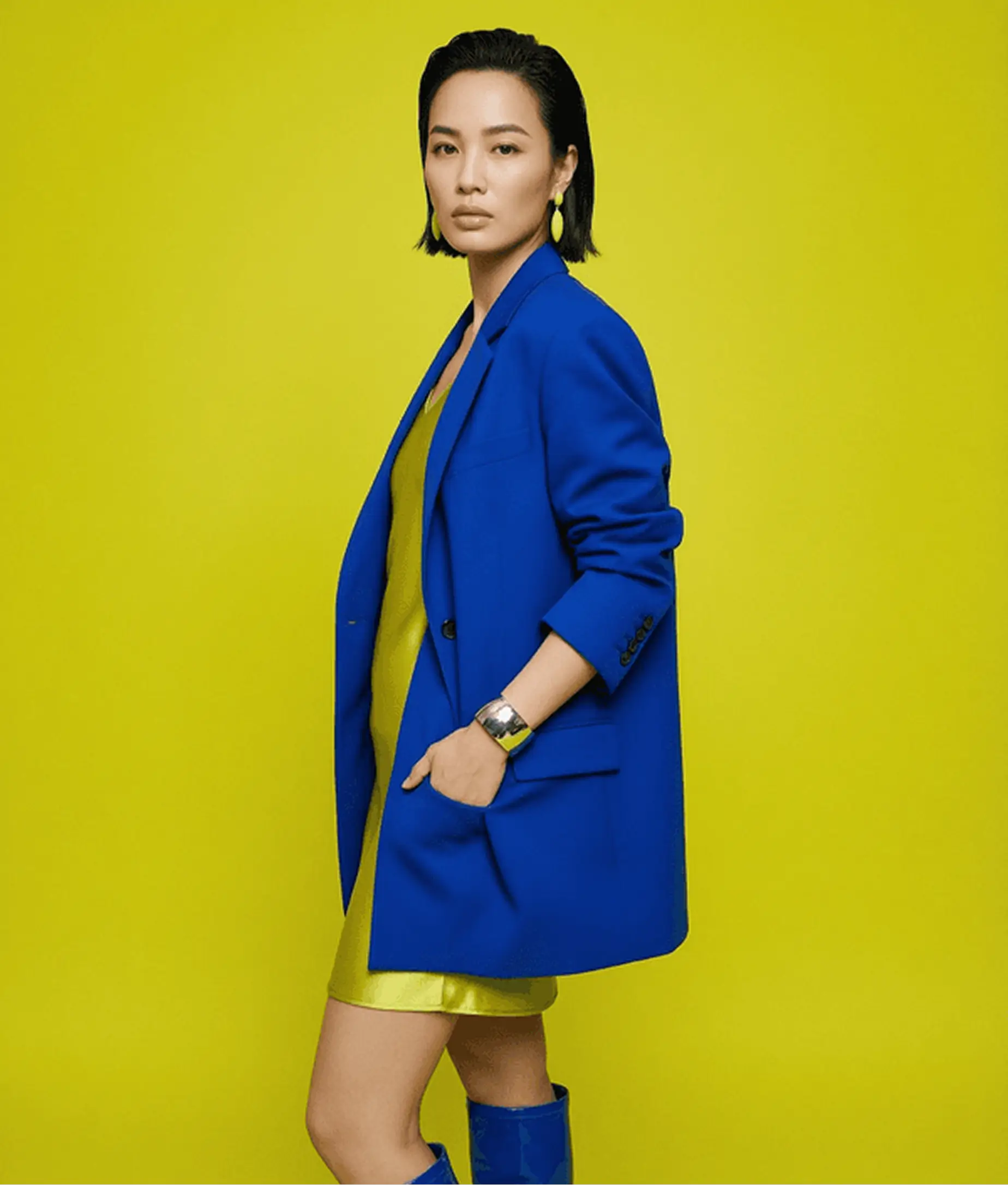 AI model photography example showing Asian woman in bold color fashion shoot wearing royal blue oversized blazer against vibrant yellow background