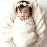 Newborn baby wrapped in a soft blanket with floral headband